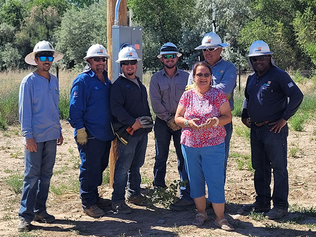PNM crew members join Sona Francis Shorthair (center, pink shirt) to celebrate connecting her home to the power grid.